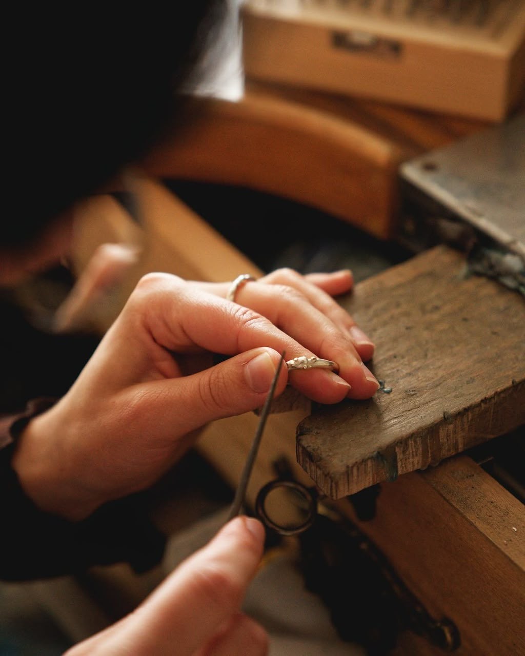 Hands filing a handmade S925 silver ring at a Maadin Artistry workbench
